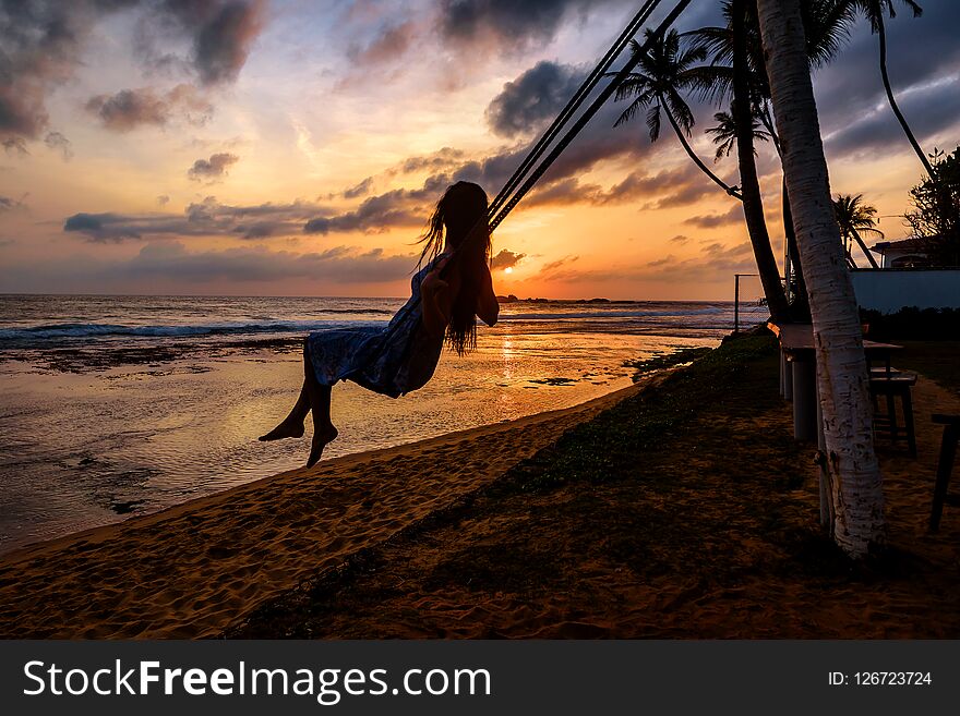 The silhouette of a lonely young woman swaying at the beach at sunset. The silhouette of a lonely young woman swaying at the beach at sunset