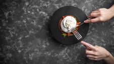 Woman Eating Burrata Cheese On Small Wooden Plate Served With Fresh Tomatoes And Basil On Dark Textured Background Royalty Free Stock Photography