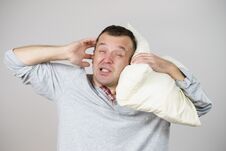 Sleepy Man With Pillow Closing His Ear Royalty Free Stock Photo
