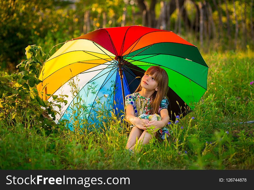 Happy child girl walk with multicolored umbrella under summer rain