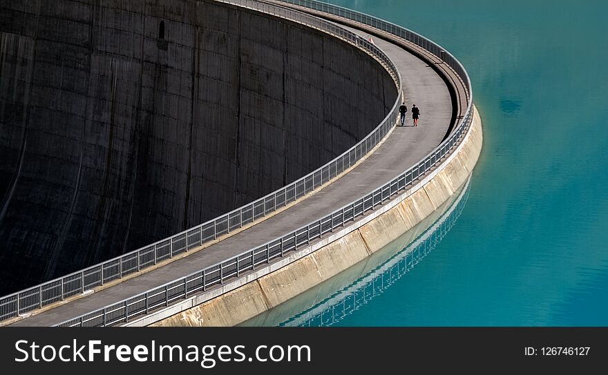 Two people walking on a dam wall Valais, Switzerland