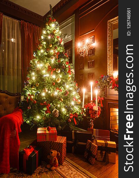 Gifts at the Christmas tree. Christmas evening by candlelight. classic apartments with a fireplace.