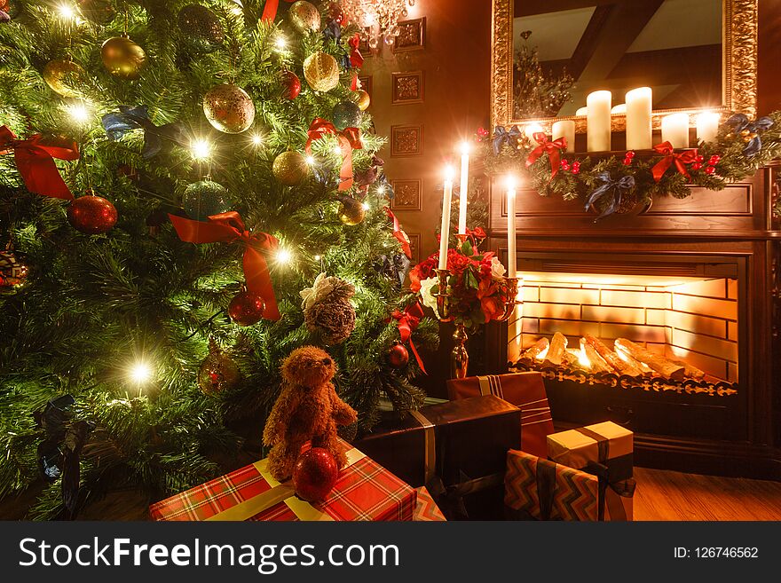 Gifts at the Christmas tree. Christmas evening by candlelight. classic apartments with a fireplace.