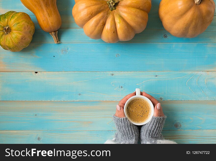 Woman`s hands in sweater holding cup of coffee on the blue wooden table. Holiday concept. Girl holding a coffee cup on a wooden vintage background - winter time concept.Holiday concept. Woman`s hands in sweater holding cup of coffee on the blue wooden table. Holiday concept. Girl holding a coffee cup on a wooden vintage background - winter time concept.Holiday concept.