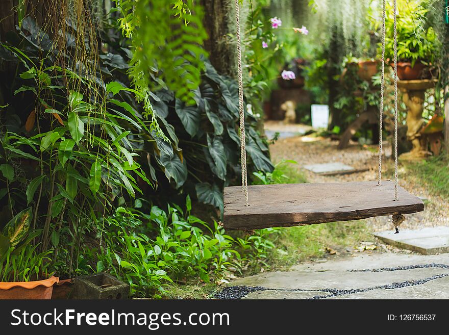 Wood swing in the green garden in the midst of nature.