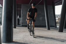 Sportsman Riding Bike Next To Modern Building Inside Urban Bridge. Stock Image