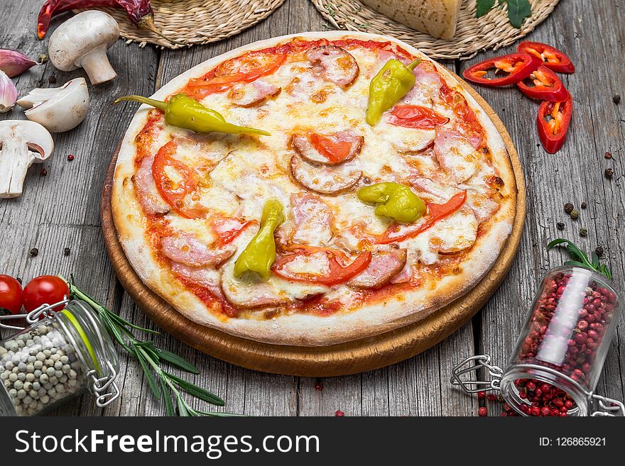 Pizza with tomatoes, mozzarella cheese, black olives and basil. Delicious italian pizza on wooden pizza board. Table top view. Pizza with tomatoes, mozzarella cheese, black olives and basil. Delicious italian pizza on wooden pizza board. Table top view