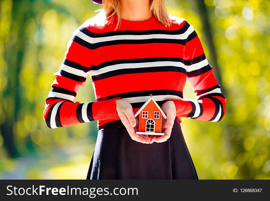 Girl holding a house toy in a hands in autumn season park. Girl holding a house toy in a hands in autumn season park