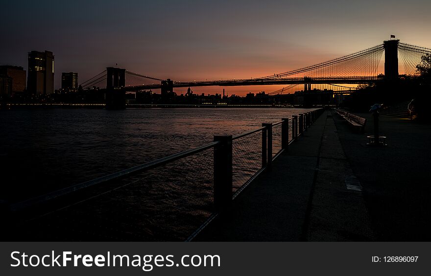 Silhouette Of The Brooklyn Bridge At Sunrise With Reflection In