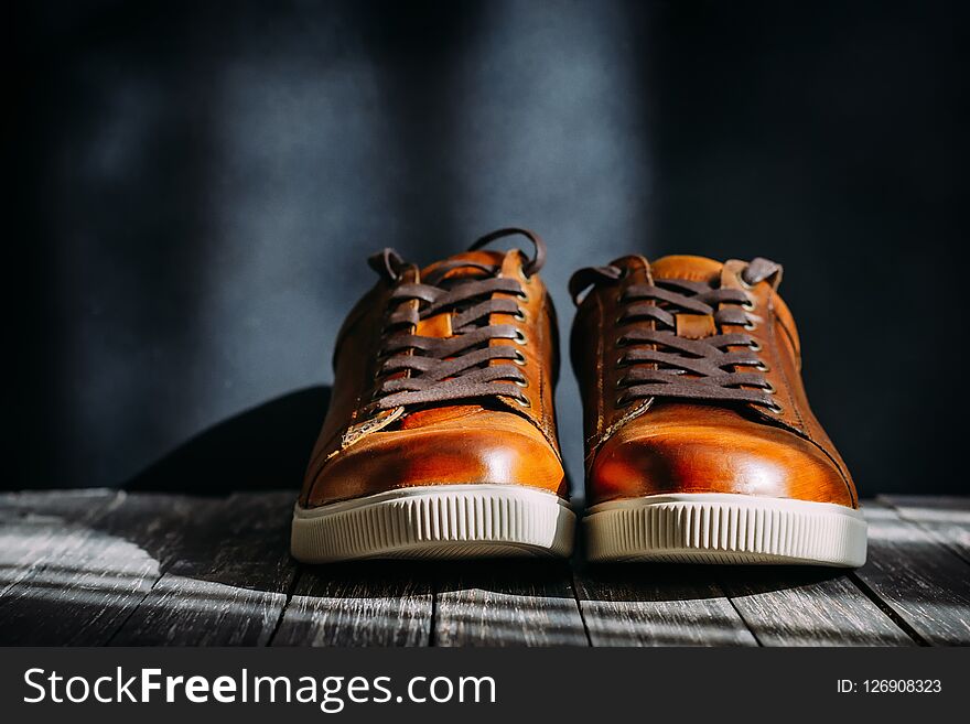 Men`s brown leather shoes with shoelaces on dark wooden background