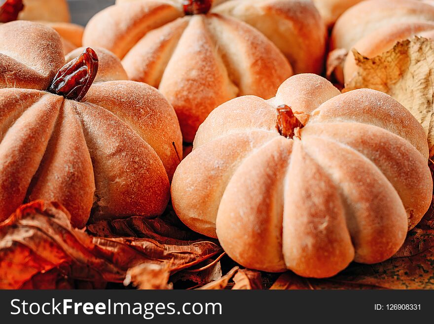 Homemade cakes in the shape of pumpkin with autumn leaves close up. Halloween sweets concept