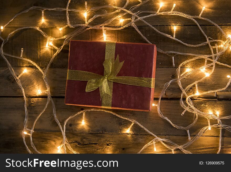 Christmas gift and lights on vintage wooden background