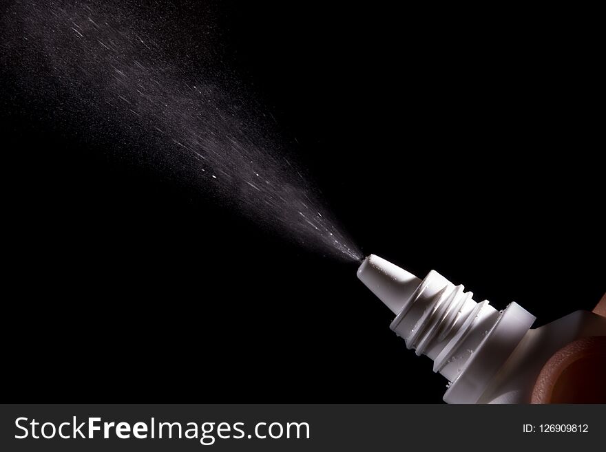 Spray for nose sprayed in the air on a black background.