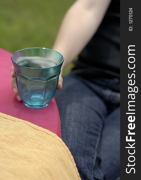 Female hand holding a turquoise glass on purple tablecloth