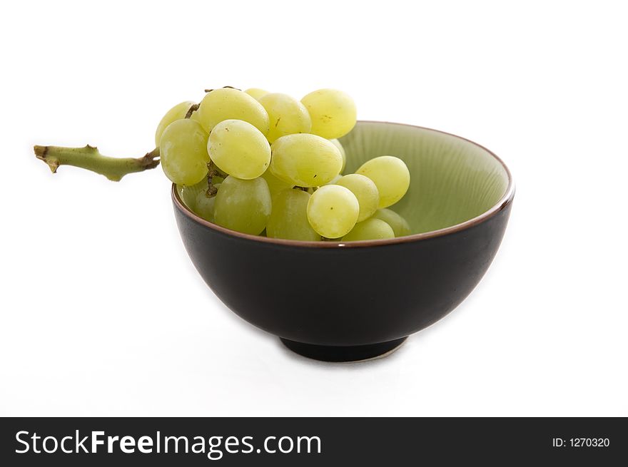 Green and black bowl full of frosty green grapes on a white background. Green and black bowl full of frosty green grapes on a white background.