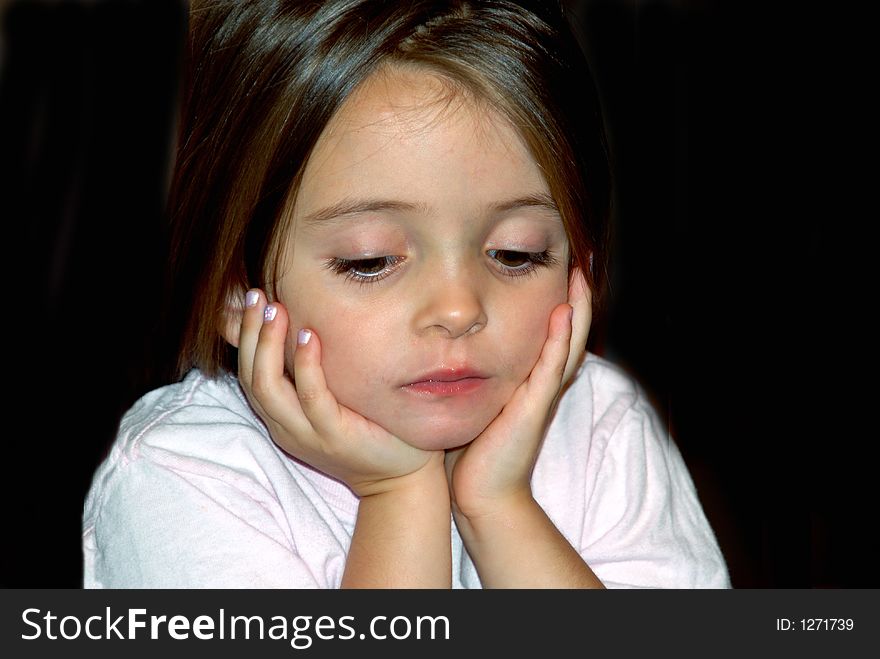 A beautiful young girl looking down with her hands on her face in deep thought. A beautiful young girl looking down with her hands on her face in deep thought.