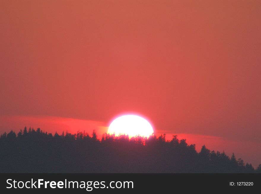 Sunset red over trees clouds clear sky