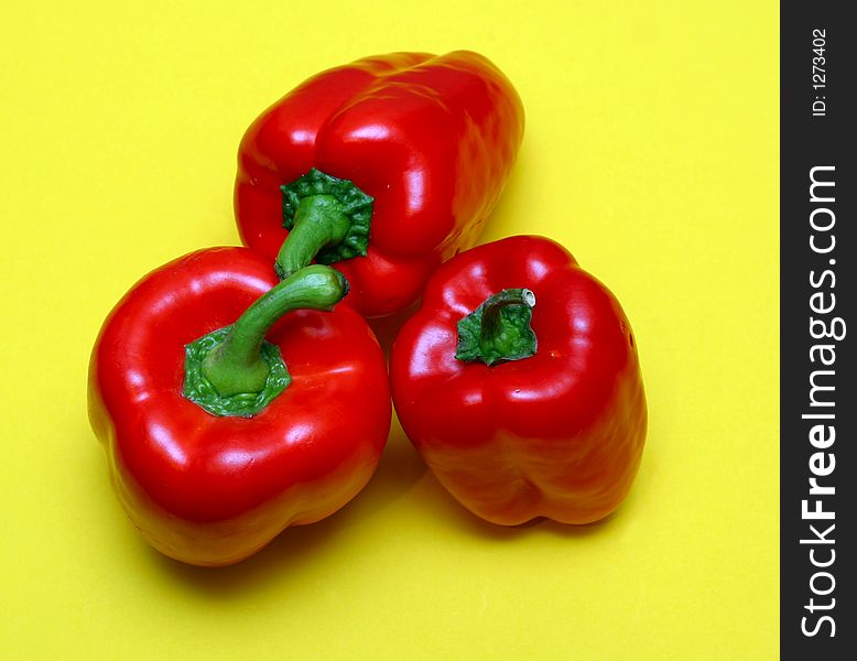 Three red peppers on a yellow paper