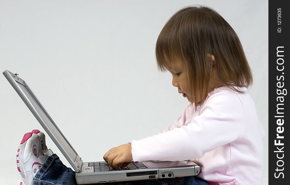 A young girl playing with a laptop computer. A young girl playing with a laptop computer