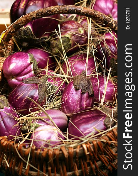 Colored eggplants in a basket with straw.