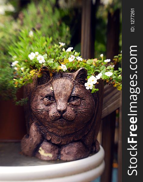 Cat figure planter with flowers on a table in the garden. Cat figure planter with flowers on a table in the garden.