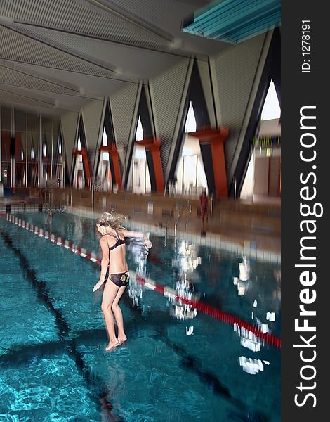 Indoor swimming pool fun, girl diving, motion blur