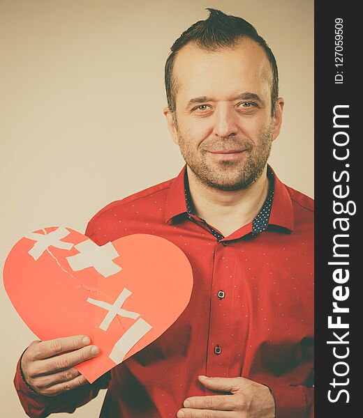 Healed love. Valentines Day concept. Adult smiling man holding big red heart with plaster. Male healing relationship. Healed love. Valentines Day concept. Adult smiling man holding big red heart with plaster. Male healing relationship.