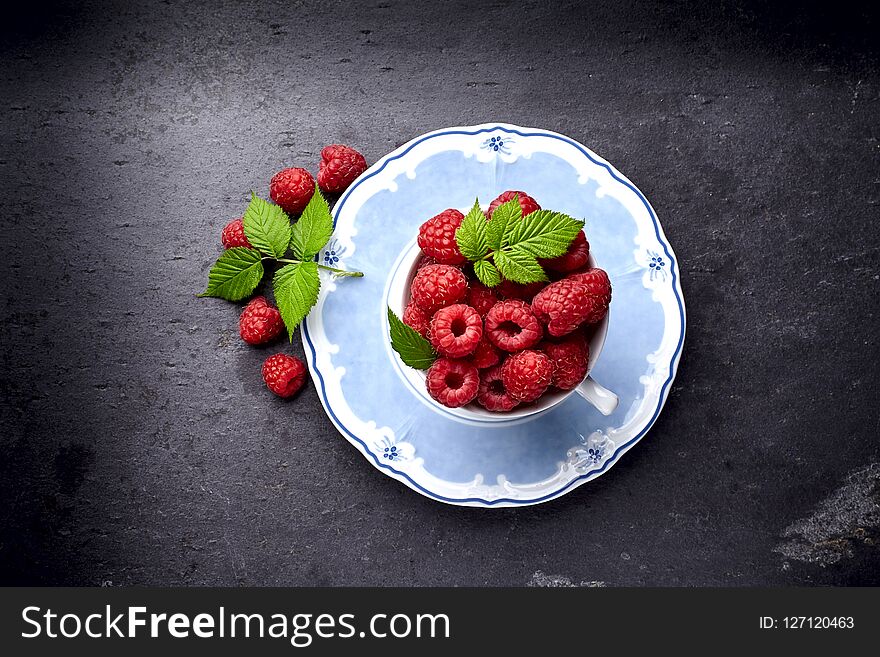 Raspberry in cup on a black background. Fresh berry with leaves. Raspberry in cup on a black background. Fresh berry with leaves.