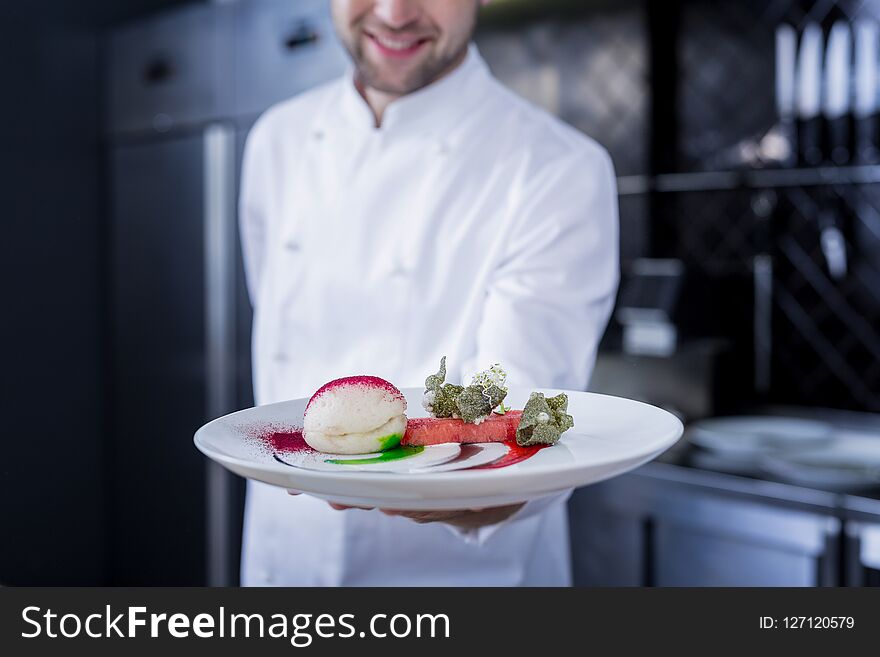 Ready. Smiling happy cook feeling excited while holding a prepared dish. Ready. Smiling happy cook feeling excited while holding a prepared dish