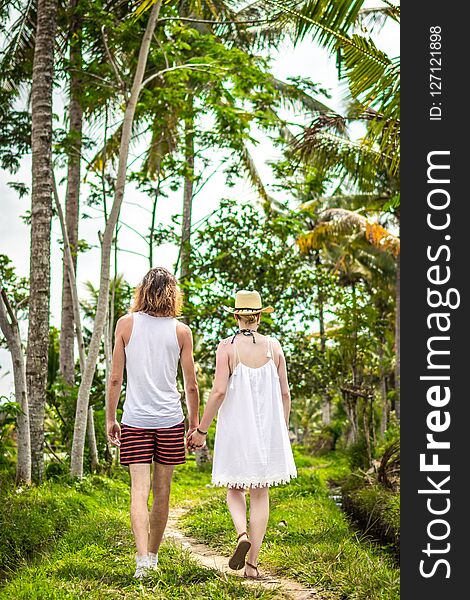 Young honeymoon couple walking among rice fields. Beautiful trip of newleds to Bali island, Indonesia. Nature, summer