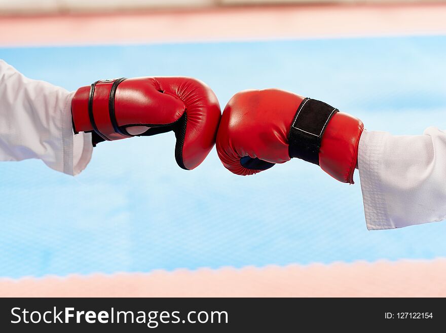 Close up of red boxing gloves hitting together at bright class.