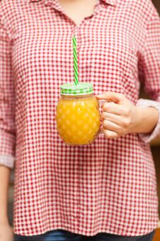 Girl In A Red Shirt Holding A Jar With Juice In The Form Of Pineapple Stock Photo