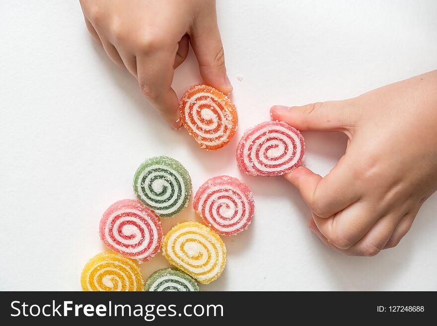 Colored marmalade of a snail shape. Sugar sweet Christmas candies. baby's hand takes candy. On a white background. copy space. Colored marmalade of a snail shape. Sugar sweet Christmas candies. baby's hand takes candy. On a white background. copy space