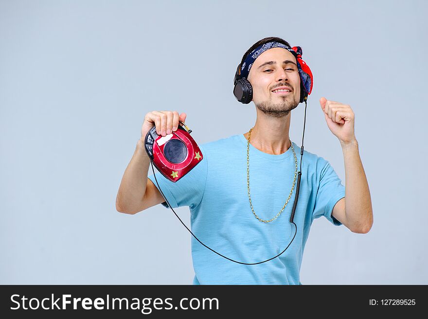 Fashionable bright man in headphones in retro style manifestation of emotions of joy, gestures with hands space for text