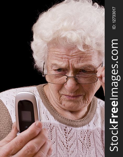 Old woman and the mobile phone isolated in black background