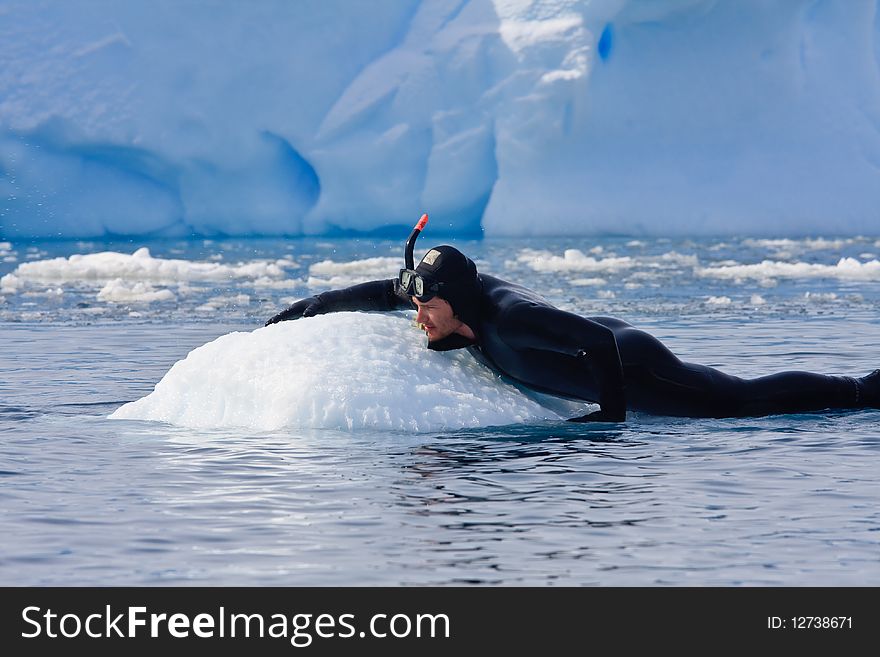 Diver on the ice against the blue iceberg. Antarctica