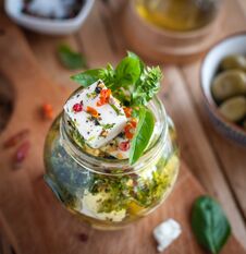 Close-up Of Marinated Feta Cheese In Olive Oil, Herbs And Red Pepper Flakes On Wooden Background Royalty Free Stock Photos