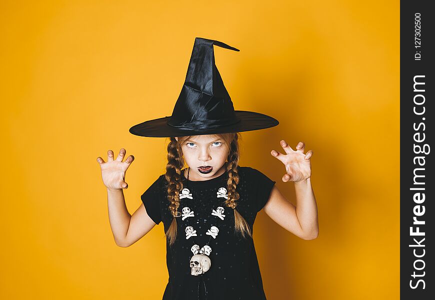 Cool and pretty young halloween witch on orange background with black hat. Cool and pretty young halloween witch on orange background with black hat