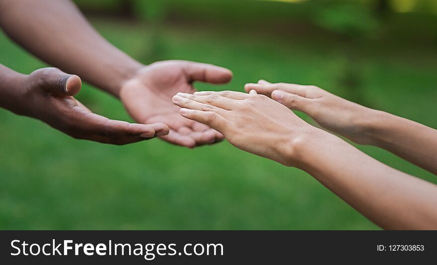 Help and support. Diverse male and female hands stretch to each other, green grass background, copy space