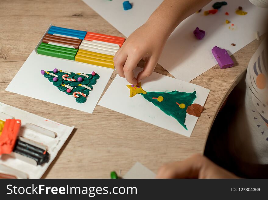 the boy makes a Christmas craft tree decorated with balls and candles made of plasticine. New Years is soon. the boy makes a Christmas craft tree decorated with balls and candles made of plasticine. New Years is soon