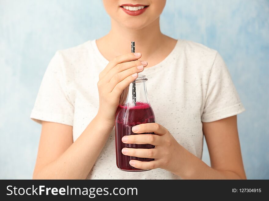 Woman with bottle of beet smoothie on light background, closeup