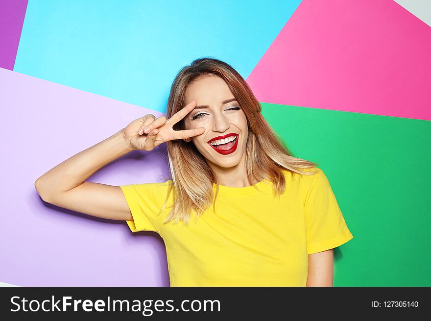 Beautiful young woman with healthy long blonde hair on color background