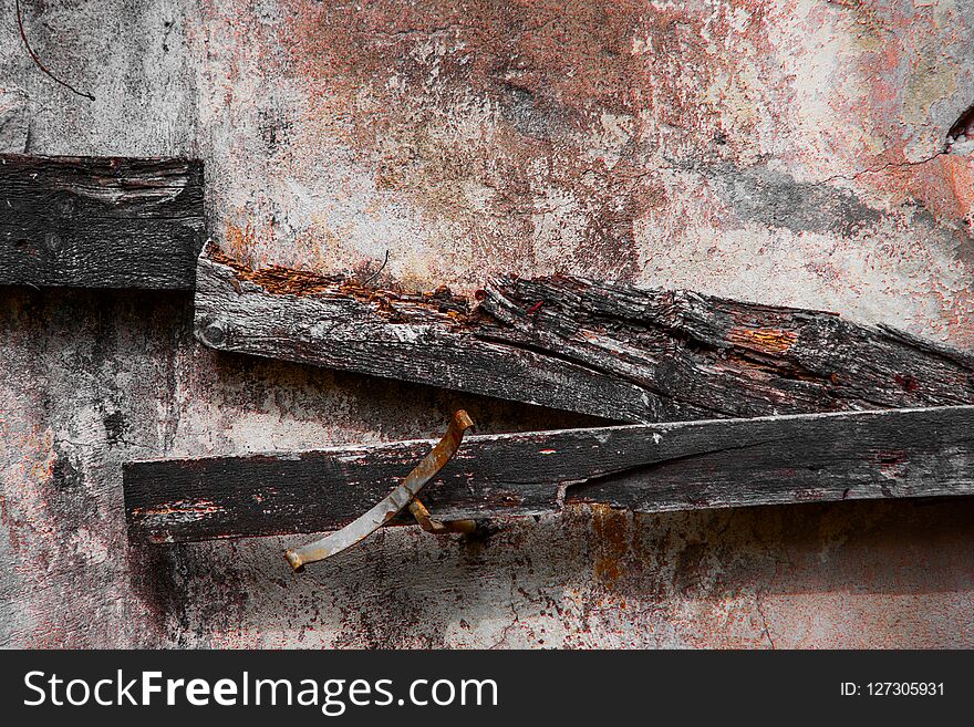 Dirty concrete wall with decaying boards and rusty pieces of metal