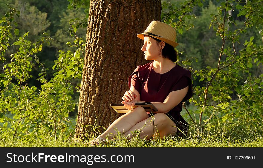 Education and business - 3. Girl sitting in the Park under a green tree and working on a tablet.