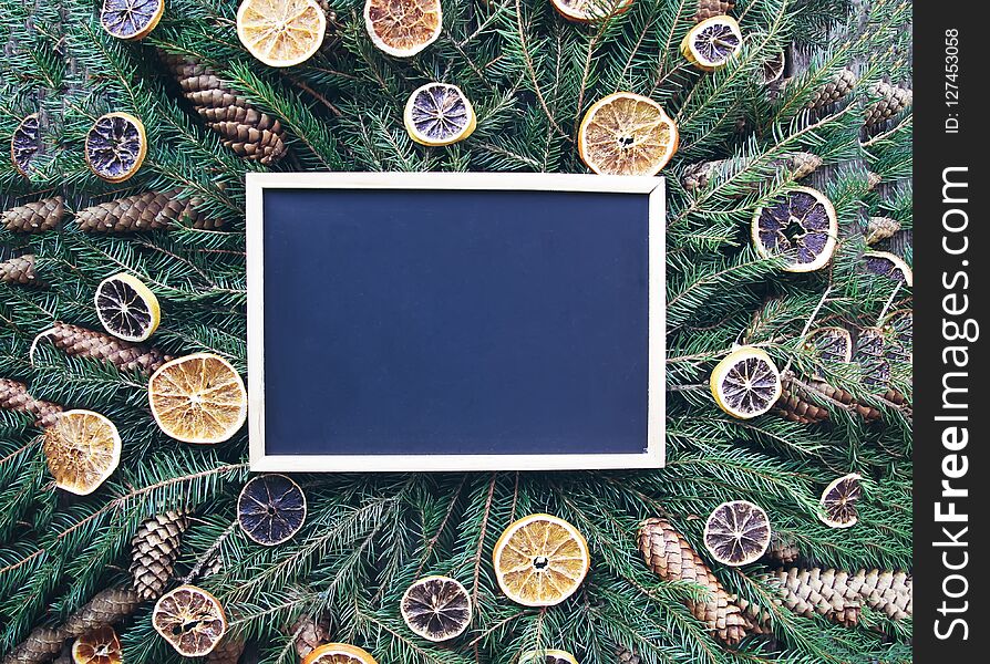 Christmas, New Year winter holiday composition. Empty framed board on green fir-tree branches decorated with dried orange slices a