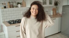 Portrait Of A Beautiful Young Woman Smiling At The Camera In A Kitchen. Royalty Free Stock Image