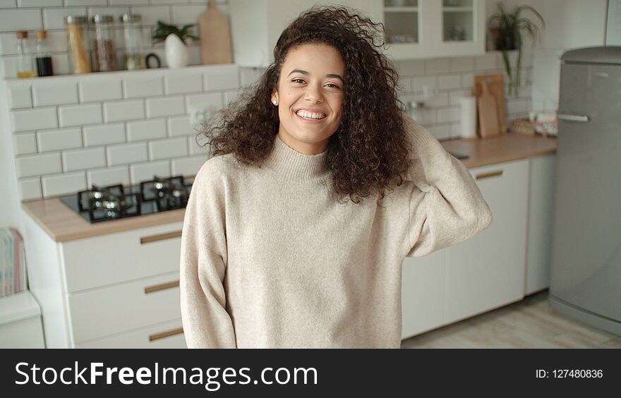 Portrait of a beautiful young woman smiling at the camera in a kitchen.