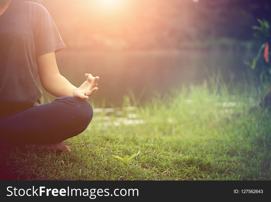 Close up of young woman doing yoga in the park with sunset