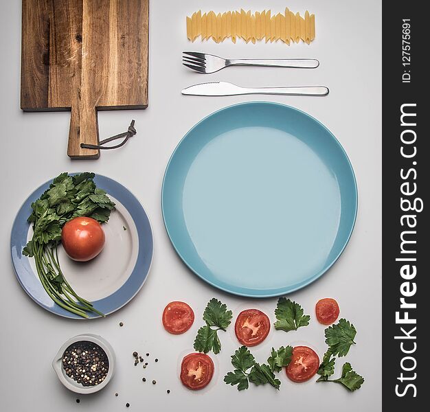 Simple food, tomato, parsley and penne pasta, lined on white background, top view flat lay