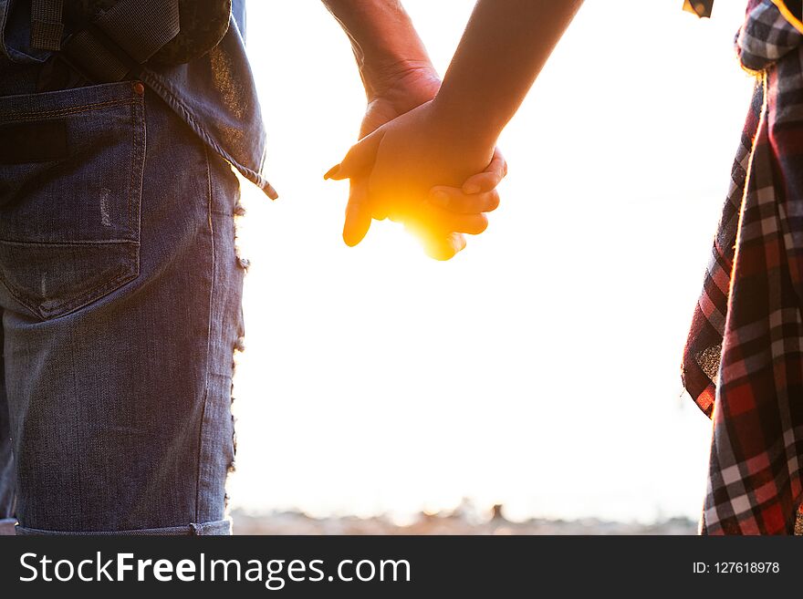 Romantic date outdoors. Young couple in love walking in the autumn park holding hands looking in the sunset